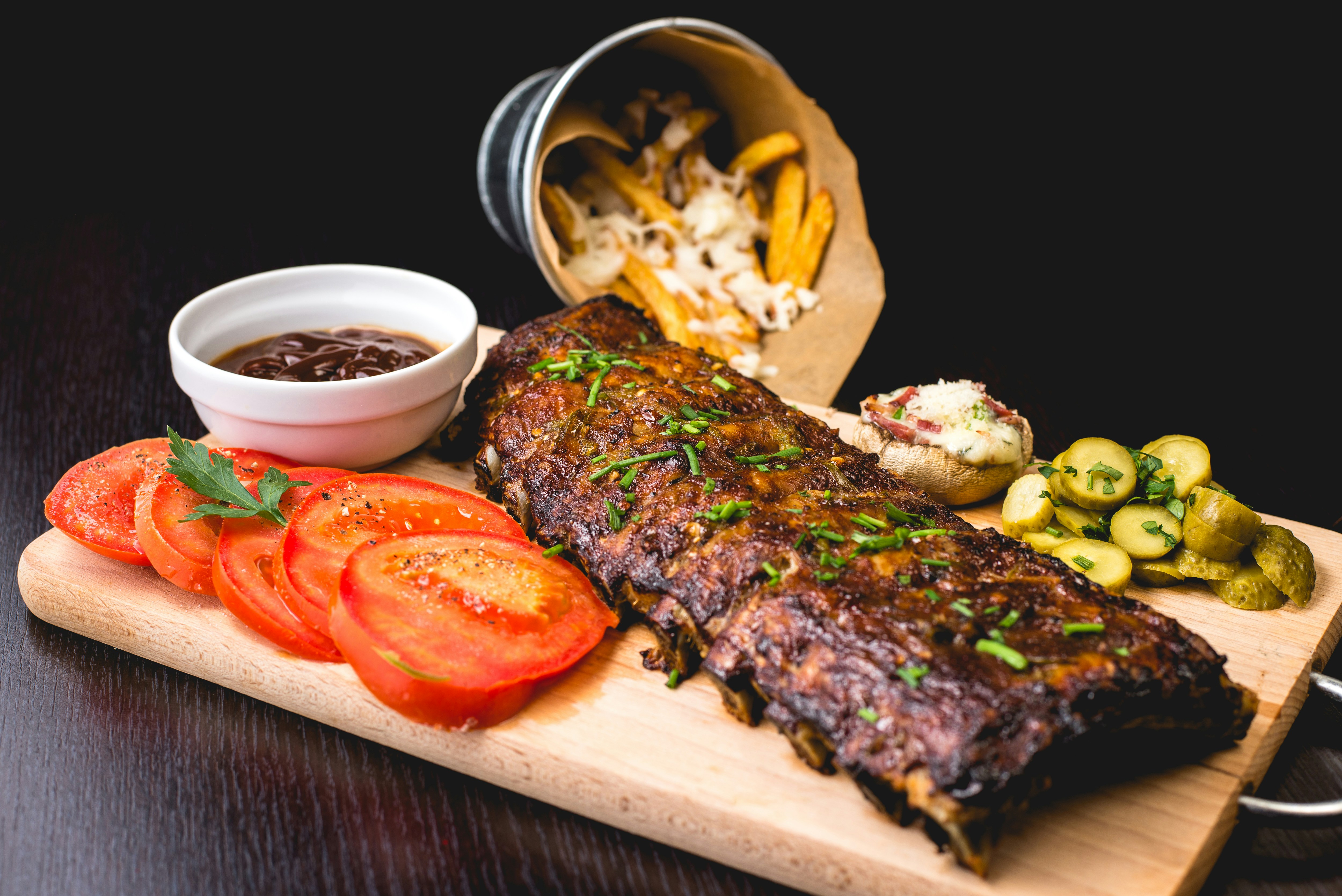Barbecue ribs served with tomatoes, pickles, sauce, and fries