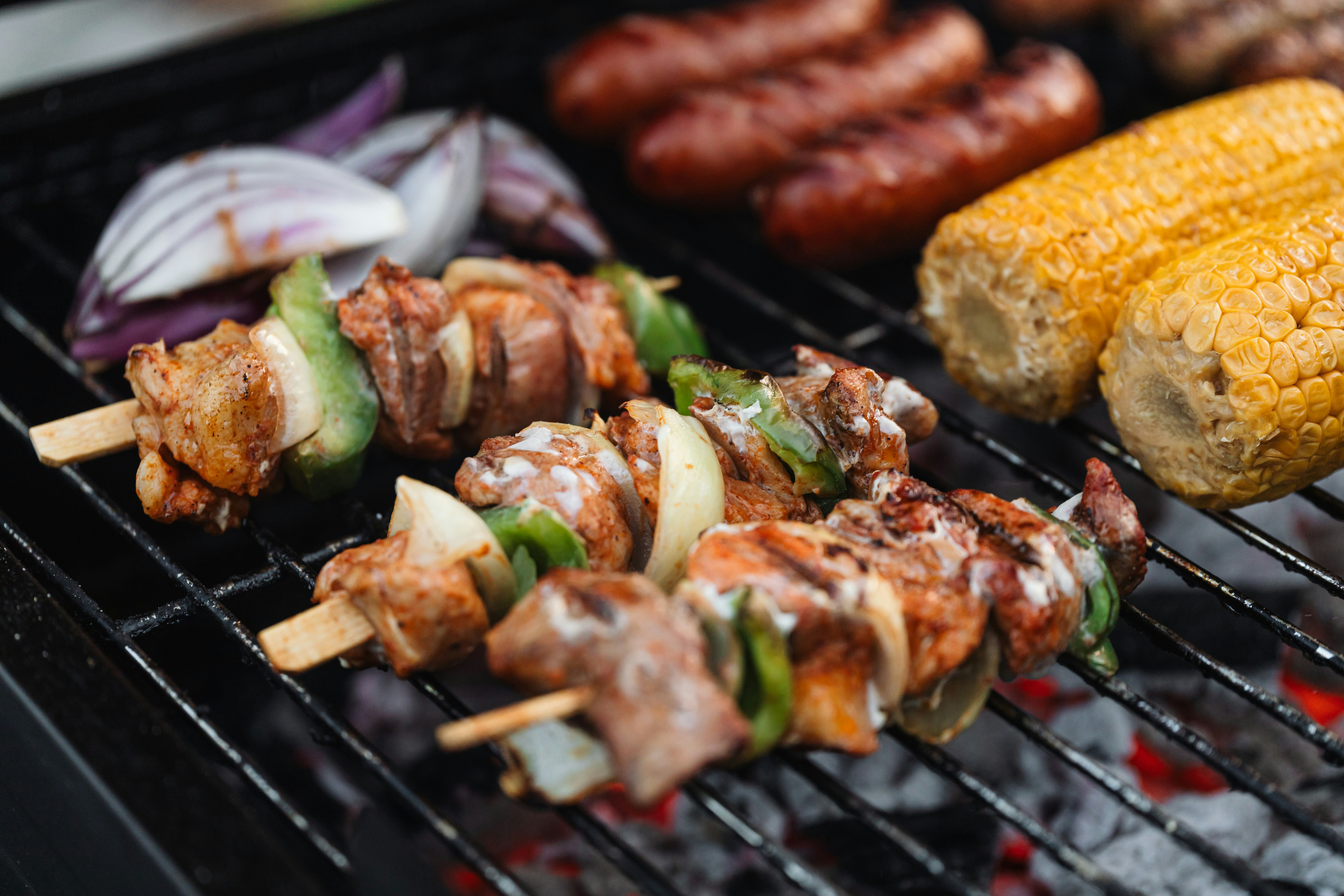 Barbecue skewers, sausage, and corn on a grill