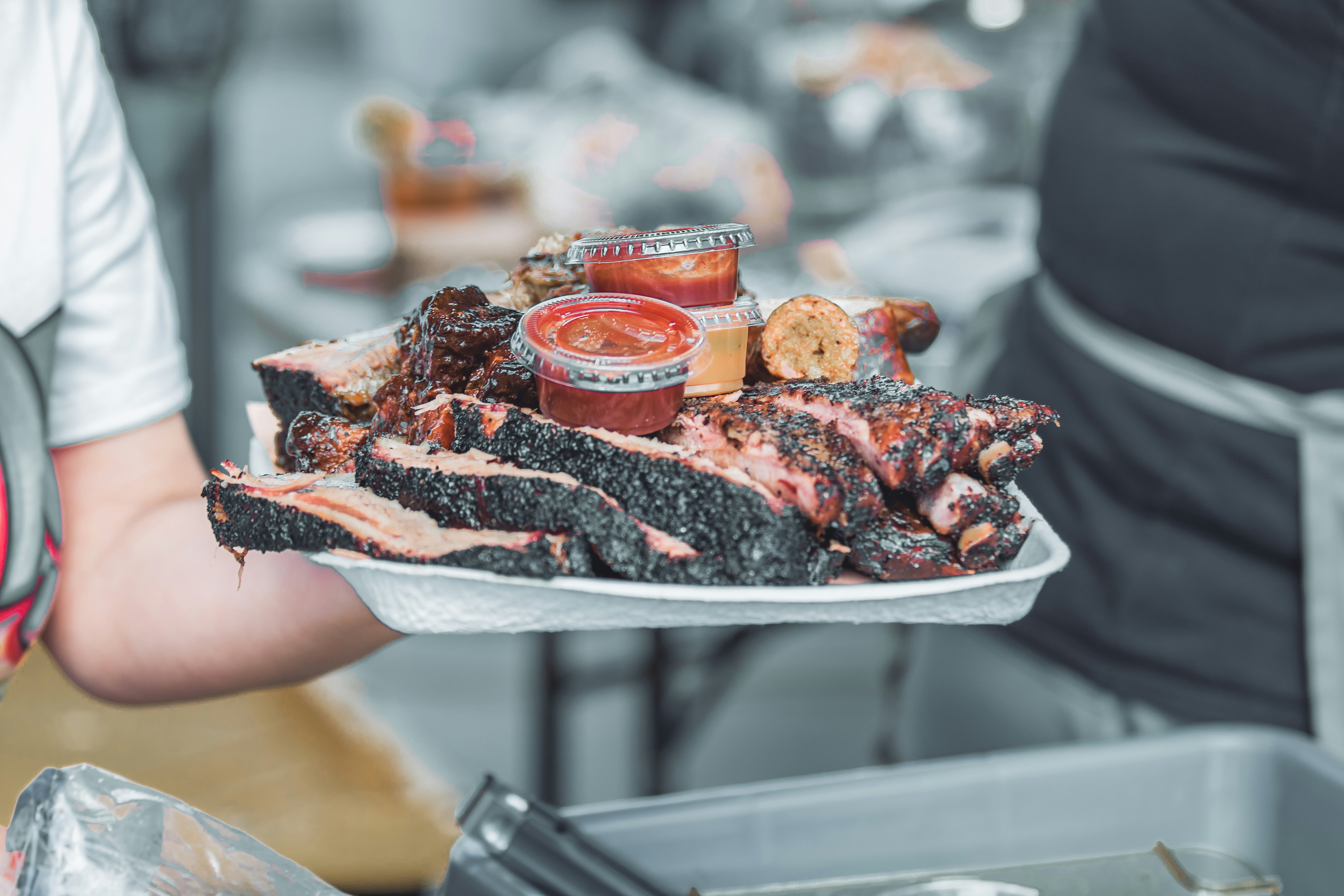 Wide barbecue takeout tray with ribs, brisket, corn, and sauce